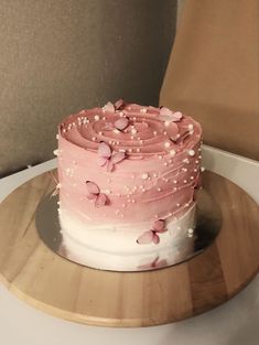 a pink and white cake on a wooden plate