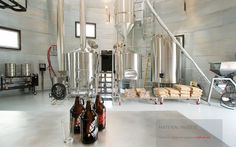 two beer bottles sitting on top of a table next to some metal tanks and stairs