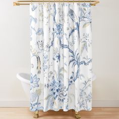 a shower curtain with blue and white flowers on it, in front of a bathtub