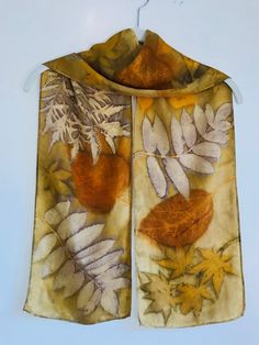 a scarf hanging on a clothes hanger with leaves and acorns printed on it