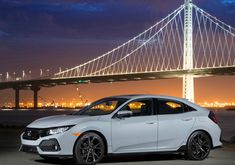 a white car parked in front of a bridge at night