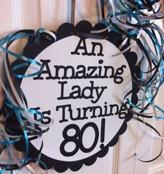 an amazing lady is turning 80 sign hanging on the door with streamers around it