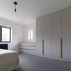 an empty bedroom with white walls and cabinets