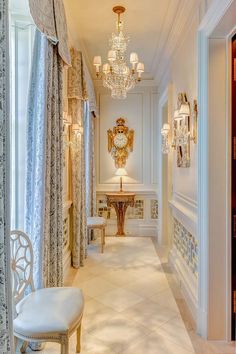 an elegant hallway with chandelier and white walls