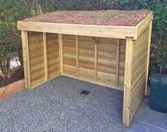 a wooden shed with plants growing on the roof