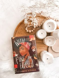 a book sitting on top of a wooden table next to candles and some white flowers