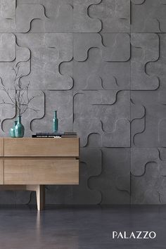 a wooden table with vases on top of it in front of a gray wall