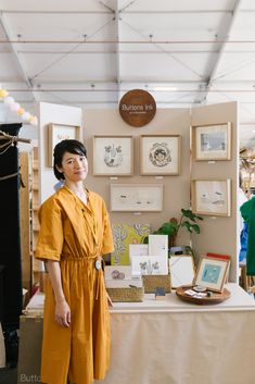 a woman standing in front of a table with pictures and other items on it,