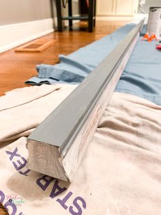 a piece of wood sitting on top of a wooden floor next to blue tarp