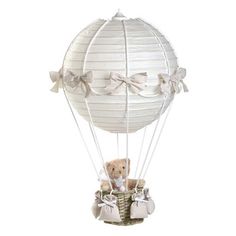 a teddy bear sitting in a basket with a balloon attached to it's side