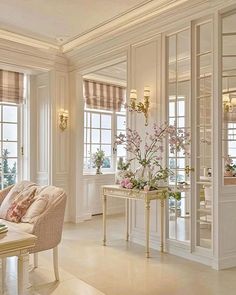 a living room filled with furniture and flowers in vases on top of a table