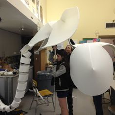 two people standing in a room with large white objects