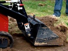 a man standing next to a red and black skid steer