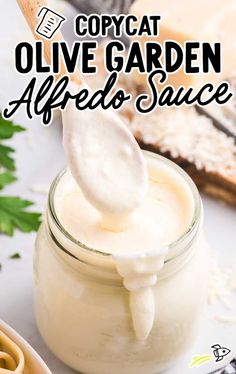 a jar filled with homemade mayonnaise sauce on top of a white table next to bread