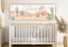 a baby's room with a white crib and pink watercolor cactus wall art