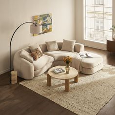 a living room with a large sectional couch and coffee table in front of a window