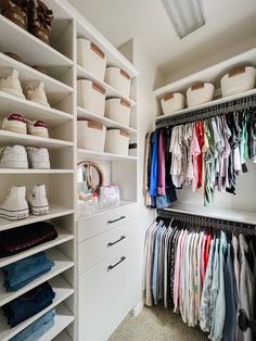 an organized closet with white shelving and lots of clothes