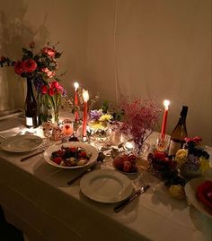 a table set with plates, candles and flowers for a dinner party or special occasion