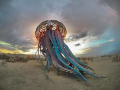 an octopus sculpture in the desert under a cloudy sky