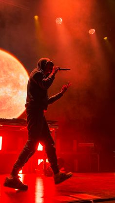 a man standing on top of a stage holding a microphone in front of a full moon