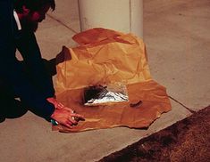 a person kneeling down next to a paper bag