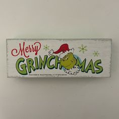 a white wooden sign that says merry grinmas