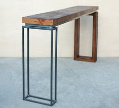 a wooden bench sitting on top of a cement floor next to a metal frame table