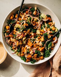 a white bowl filled with chopped vegetables next to a cup of coffee and spoons