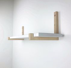 a white wall with two wooden shelves on the side and one shelf attached to the wall