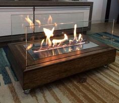 a glass fire pit sitting on top of a wooden table in front of a rug