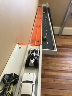 toy cars are lined up on top of the shelf in this playroom area that is built to look like a race track