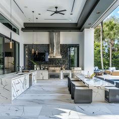 an outdoor kitchen and dining area with marble counter tops, white walls, and ceiling fan