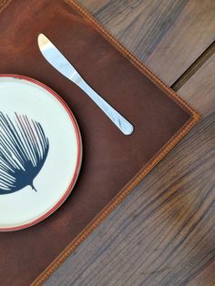 a plate with a fork and knife on it next to a leather placemat,