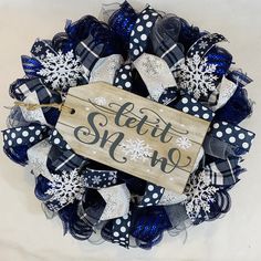 a blue and white christmas wreath with a sign that says, let it snow on the front