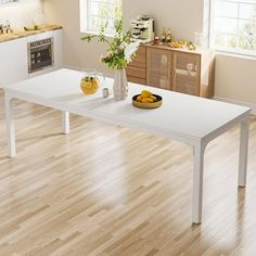 a white table sitting on top of a wooden floor next to a kitchen area with an oven