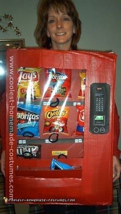 a woman is holding up a vending machine made out of candy bars and soda cans