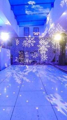 an indoor dance floor with snowflakes on it and lights shining down the center