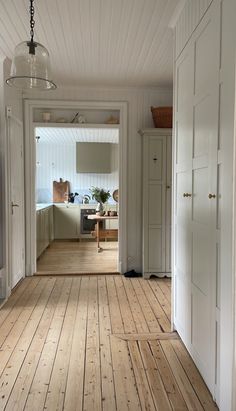 an empty room with wood floors and white walls, leading to the living room area