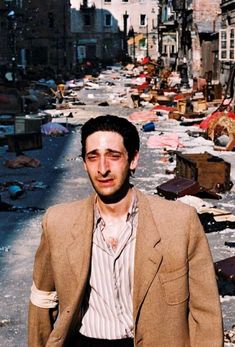 a man standing in front of a street filled with trash and debris, captioned to comidas familiares