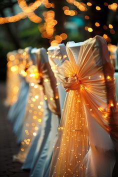 rows of chairs covered in white and gold cloths with lights on the back ground