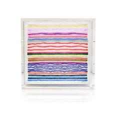 an art piece with multicolored lines on it in a glass frame, against a white background