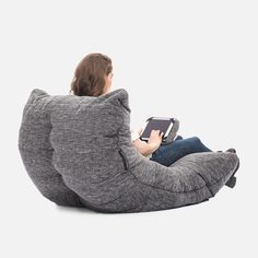 a woman sitting on a bean bag chair with an electronic device in her lap,