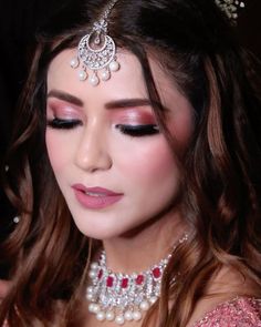 a woman wearing a tiara with pearls on it's head and makeup in front of her face