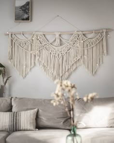 a living room with a white couch and macrame wall hanging on the wall