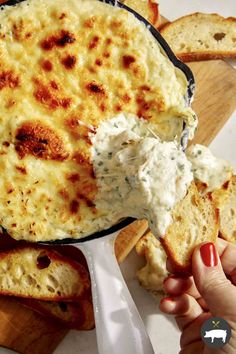 a hand holding a piece of bread with cheese on it and dip in the middle