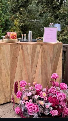 a wooden table topped with pink flowers next to a sign that reads, love is in the air