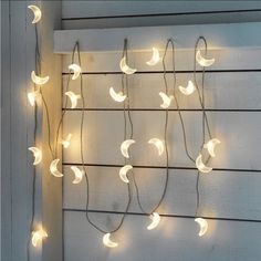 a string of lights hanging from the side of a white wooden wall next to a window