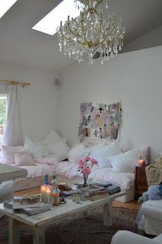 a living room filled with lots of furniture and a chandelier hanging from the ceiling