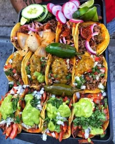 a tray filled with tacos covered in meat and veggies