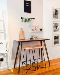 two stools sitting at a table with pictures on the wall